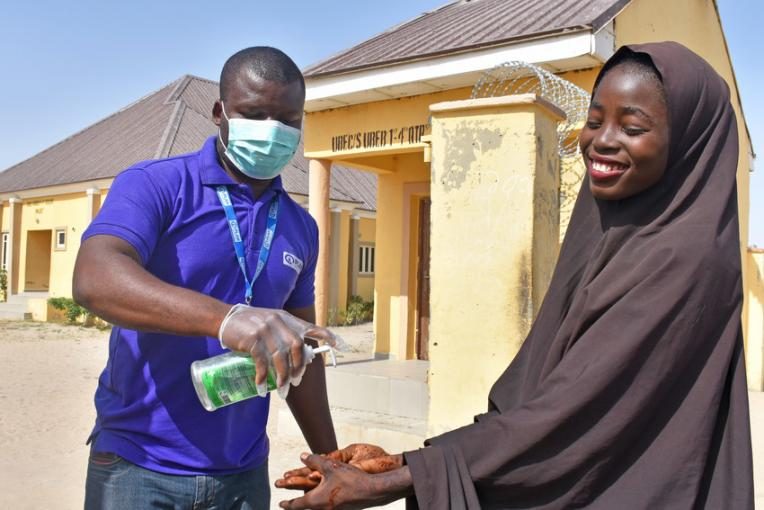 Girl receives hand sanitiser from Plan International staff in Borno state.