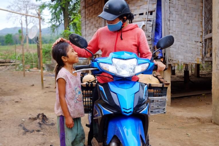 Ha on her motorbike giving her daugther, Yen Nhi, 7, a head pat