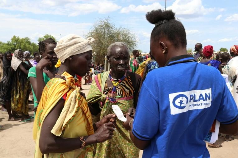 Plan International staff member talks to women at a food distribution point.