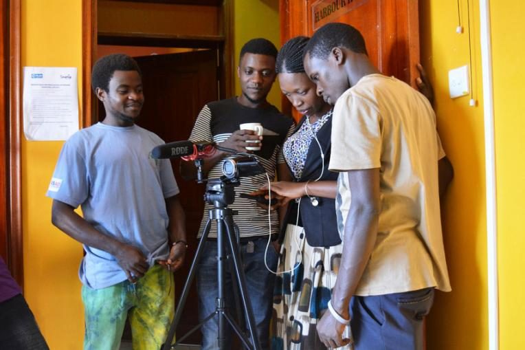 Young people learning how to use camera equipment at the SmartUp Factory in Uganda.