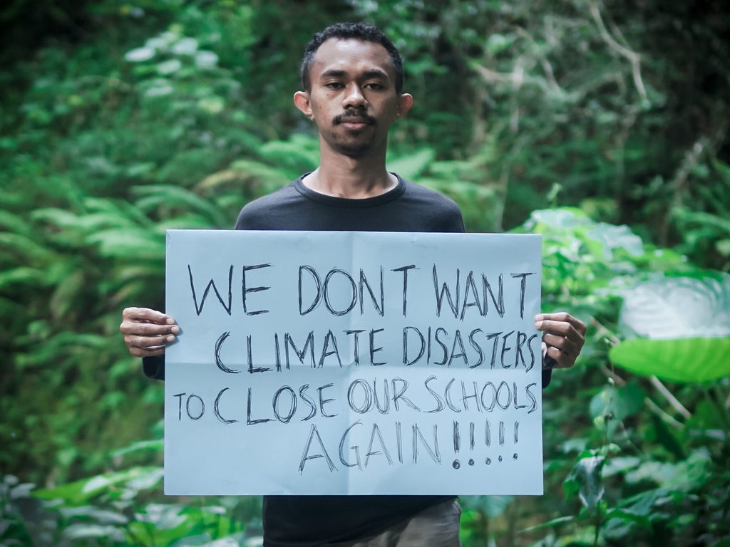 Yoris from the Y4EiE panel holding a sign: ‘We don’t want climate disasters [to] close our schools again!!!!!’