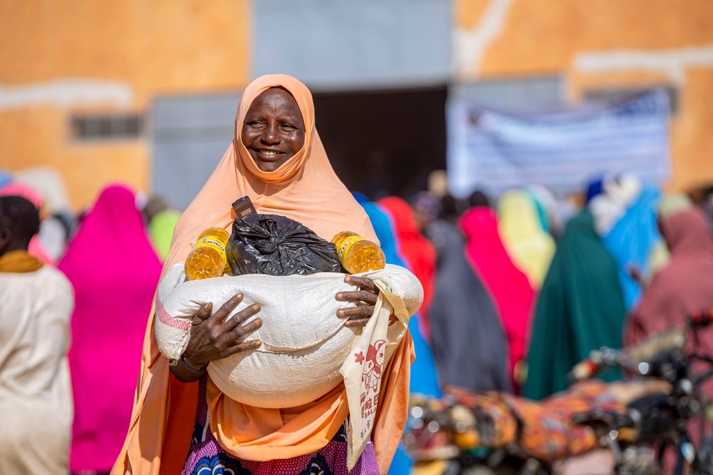Woman carrying food aid distributed by Plan International in Niger.