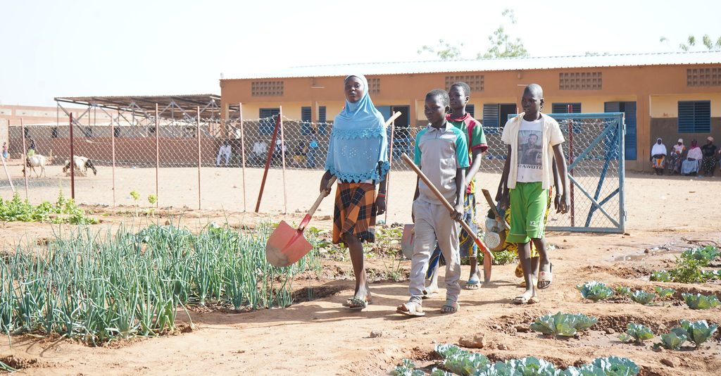 Children bring their tools to the school garden.