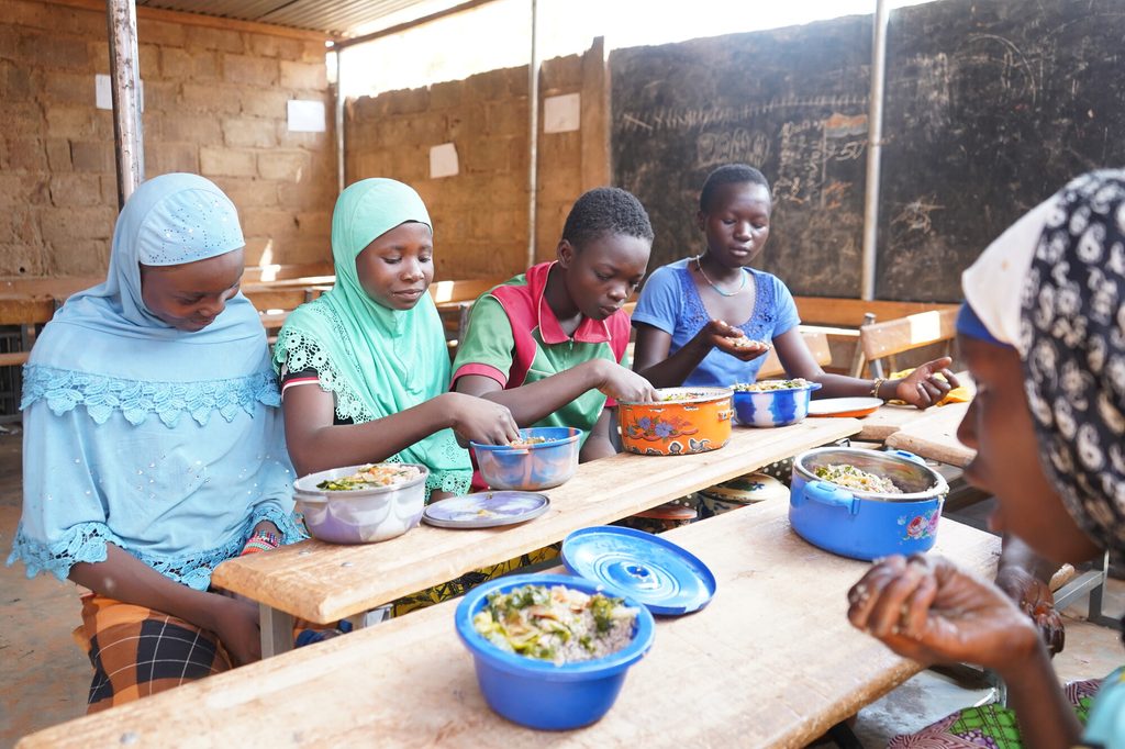 Children eat the meals prepared from vegetables in the school garden.