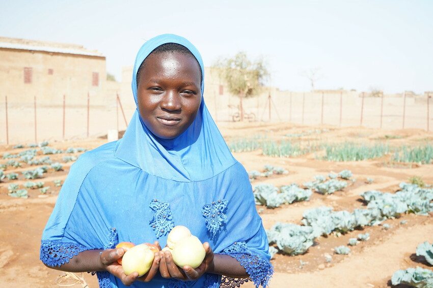 Aminata holds onions grown in the school gardening club.