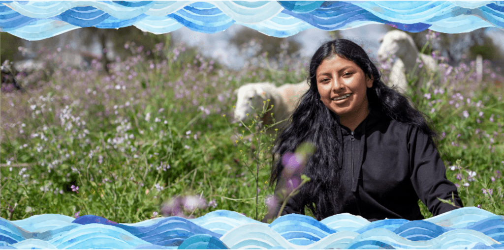 Girl sits in field with sheep.