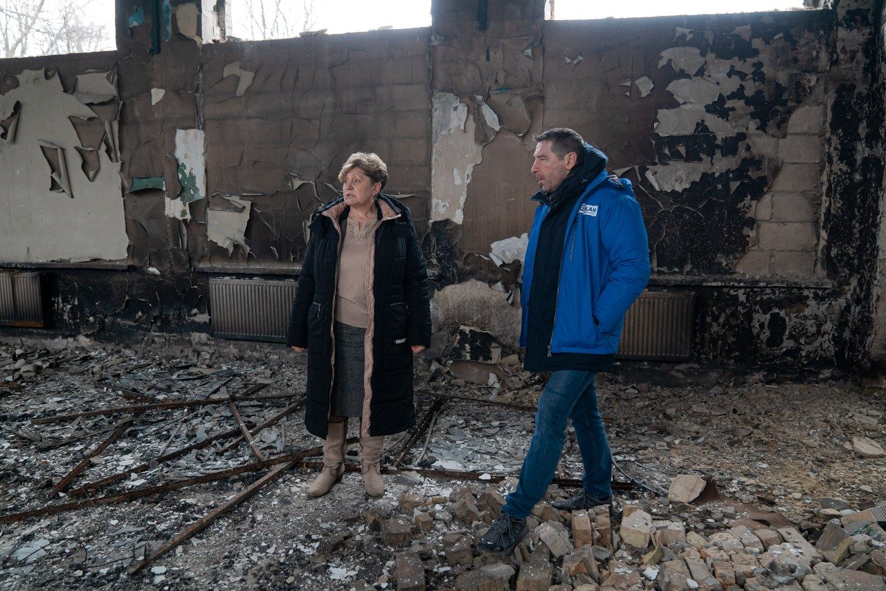 Sven Coppens and Ludmila, the headmaster, stand in the destroyed school building. Albina.