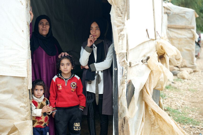 Douaa, 12, her mother and younger sisters look out from their tent in camp for Syrian refugees.