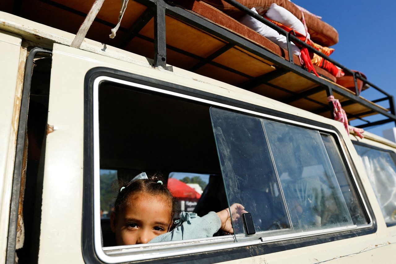 A child looks through a car window as Palestinians, who fled their houses amid Israeli strikes, take shelter in a tent camp at a United Nations-run centre in Khan Younis in the southern Gaza Strip.