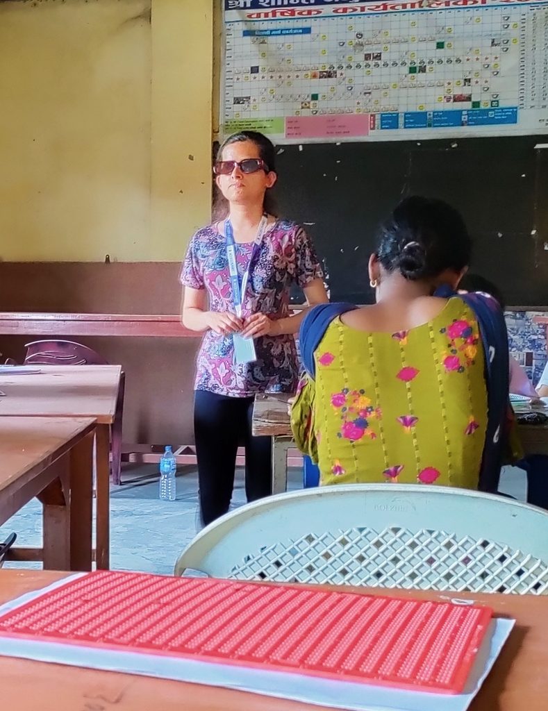 Laxmi standing at the front of a classroom hosting a workshop. 