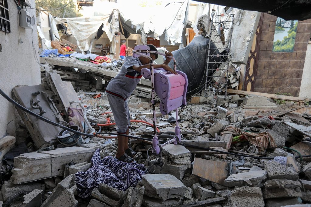 Boy salvages possessions from rubble of damaged building in Gaza city.