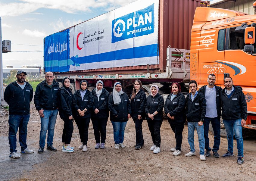 Plan Egypt staff stand in front of a truck loaded with relief supplies for Gaza. 