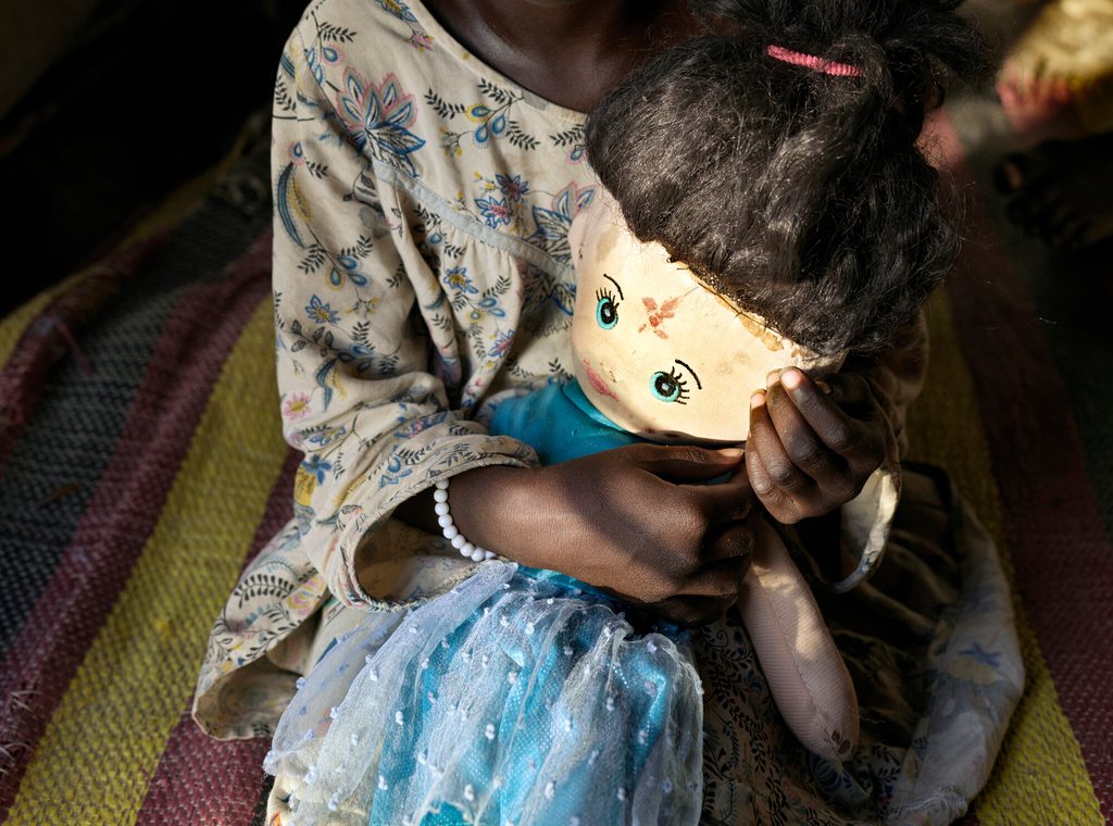 Samira’s* 5-year-old sister holds tightly onto her doll.