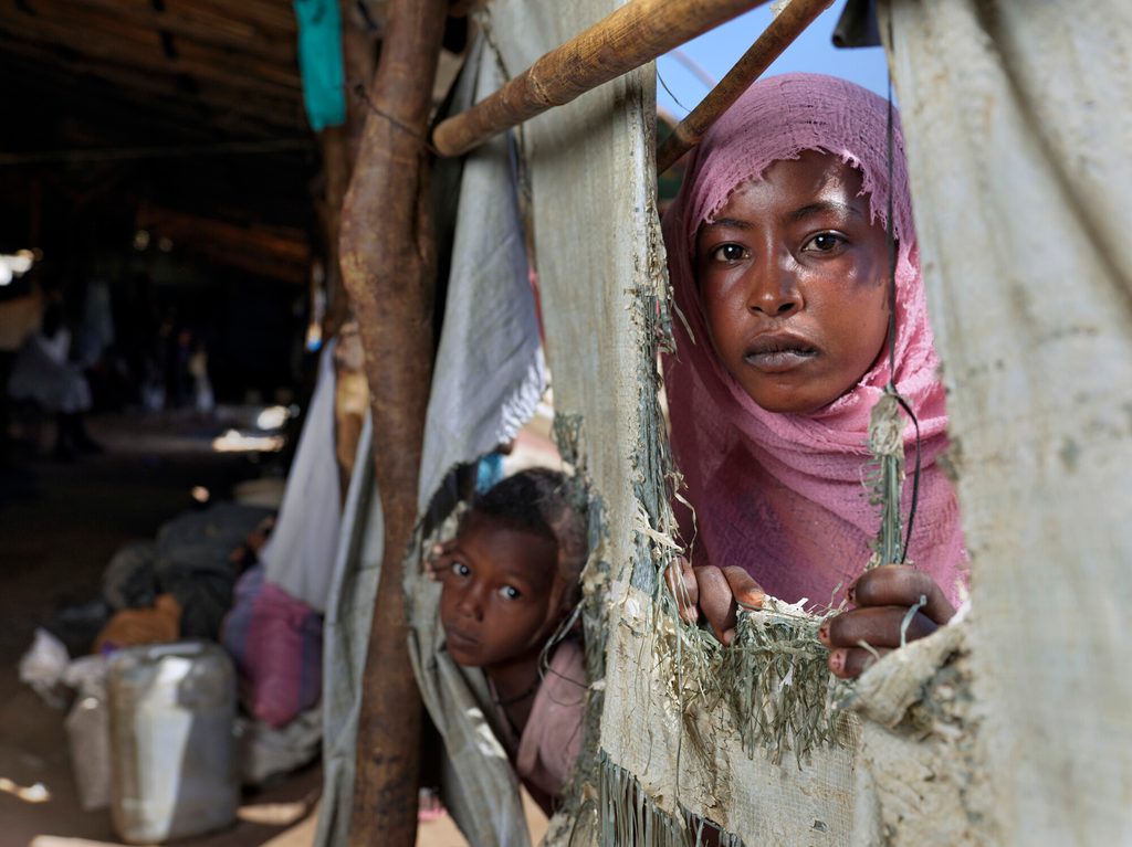 Marian, 15, looks out through gap in the shelter built by Plan.