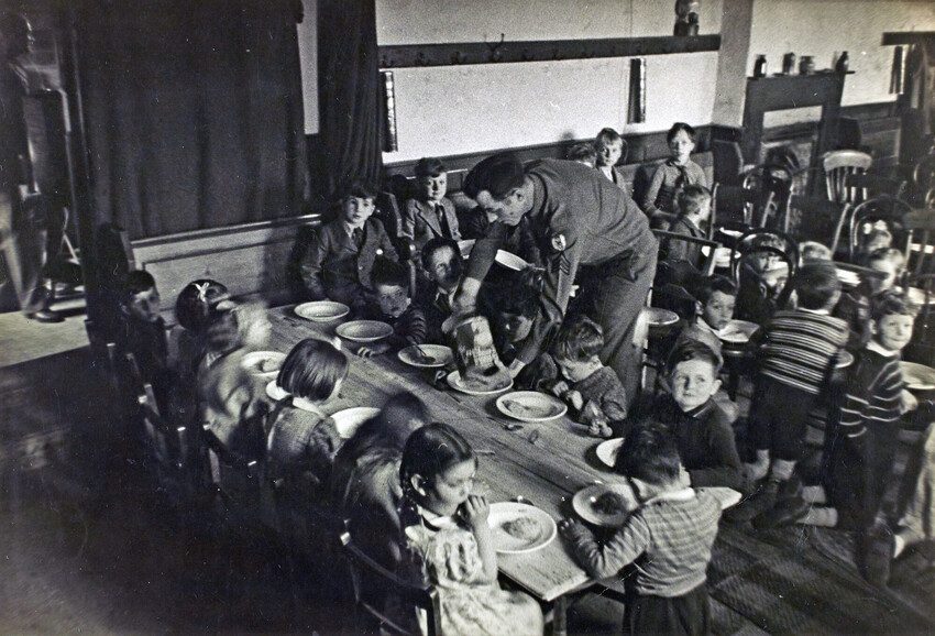 Children sitting around a table enjoying the tea party. Black and white photo 1944. 