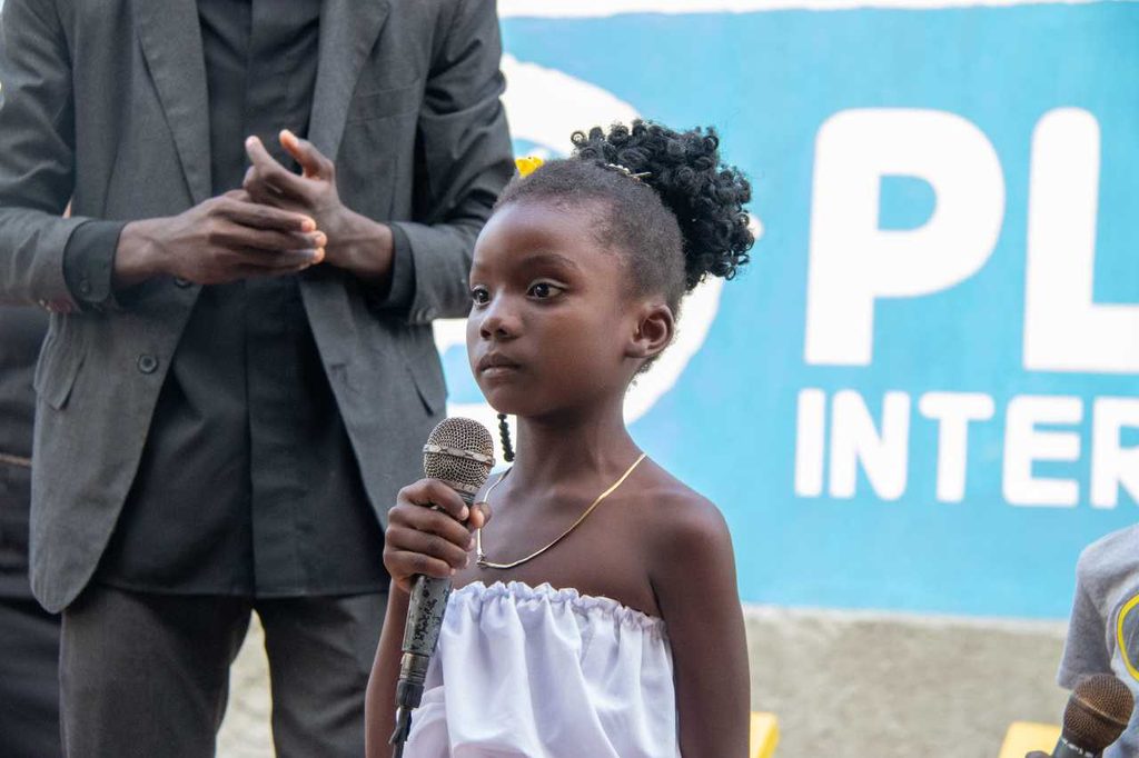 A young girl speaks into a microphone.