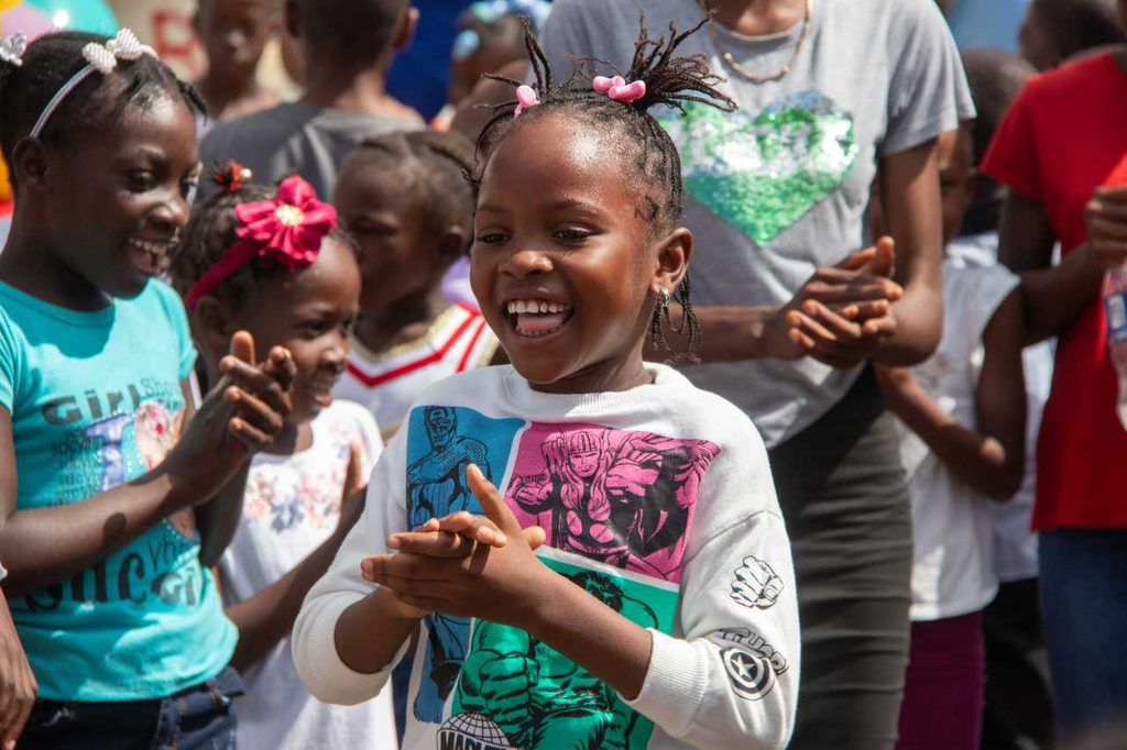 A young girl smiling and clapping during an activity.