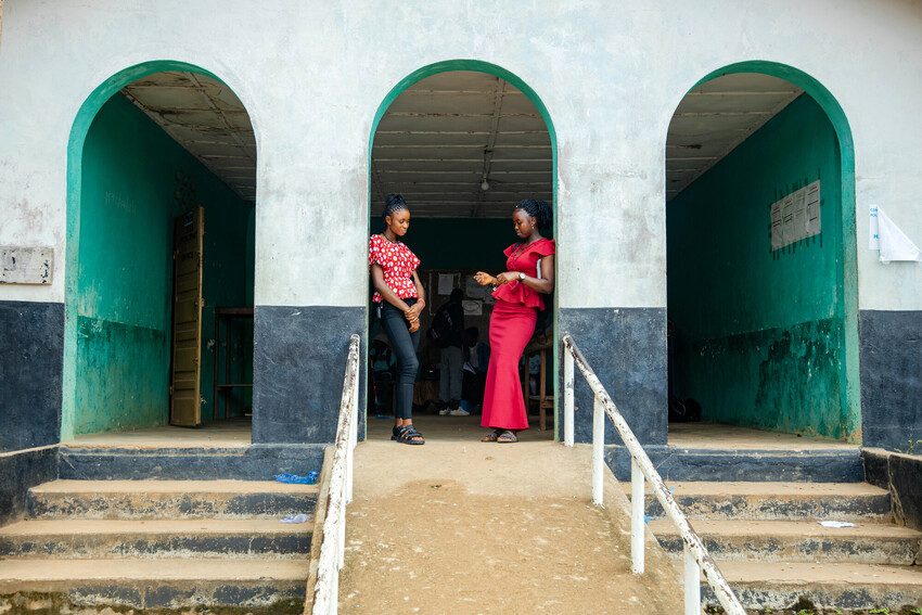 Eunice and Kumba stand in the doorway of their school. 