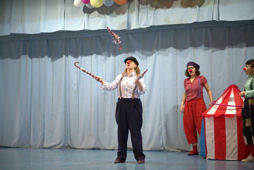 Elin the Clown juggles with umbrellas during performance.