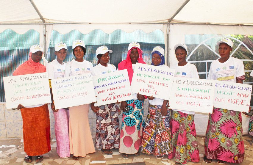 Girls advocating against FGM stand holding signs.