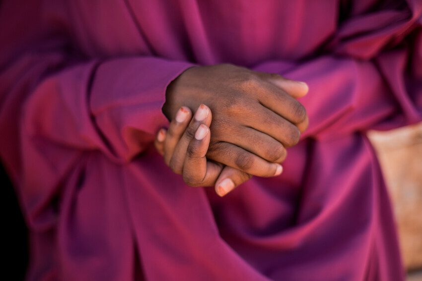 A girl from Somalia crossing her hands.