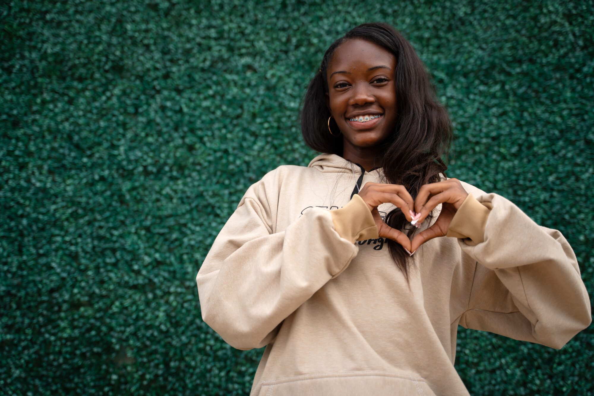 A young woman making a heart shape with her hands to show support for Unite for Peace