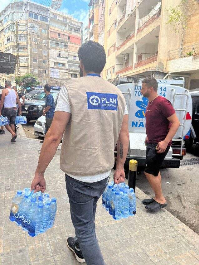 Plan staff deliver supplies like water and hygiene kits to children and families forced to flee their homes.