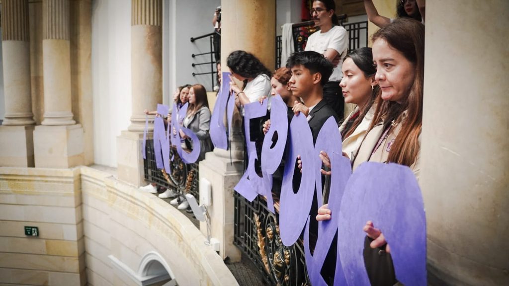 A group of people hold up letters on a balcony to make a sign.