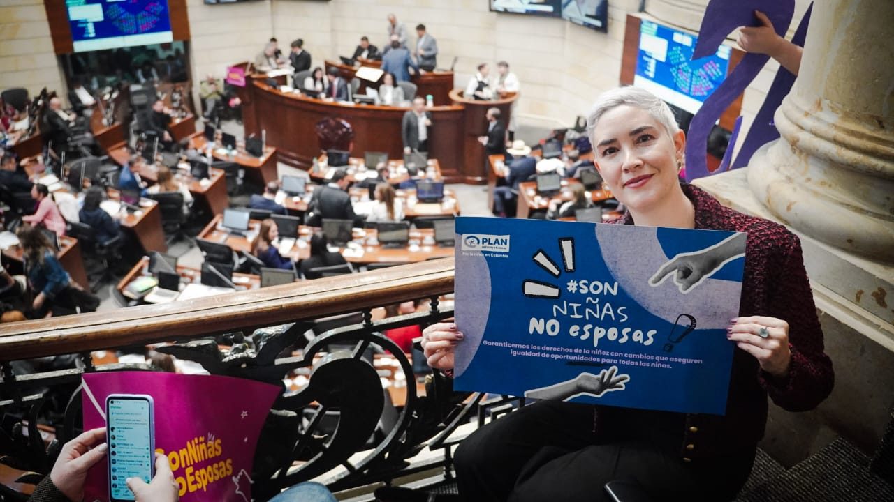 Angela Anzola holds up a poster to end child marriage on a balcony overlooking the senate. 