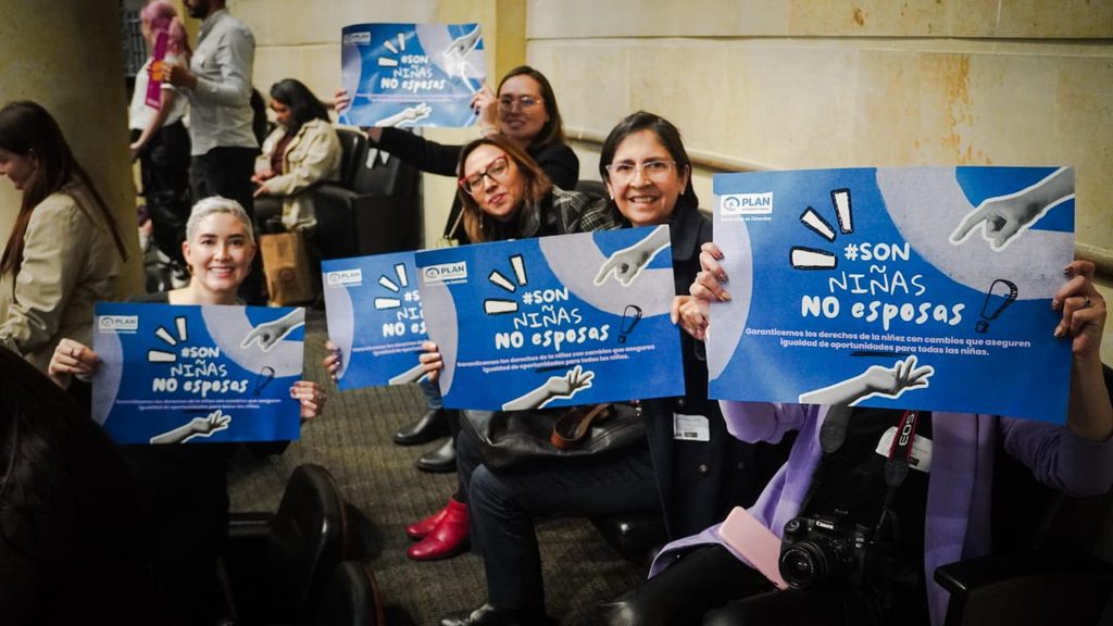 Plan International Colombia staff hold up banners.