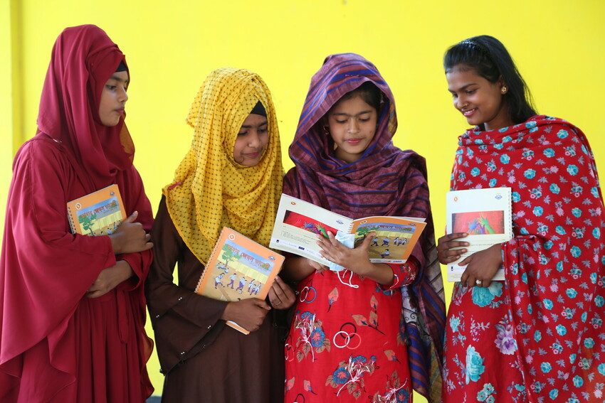 4 girls are reading GEMS programme booklets. 