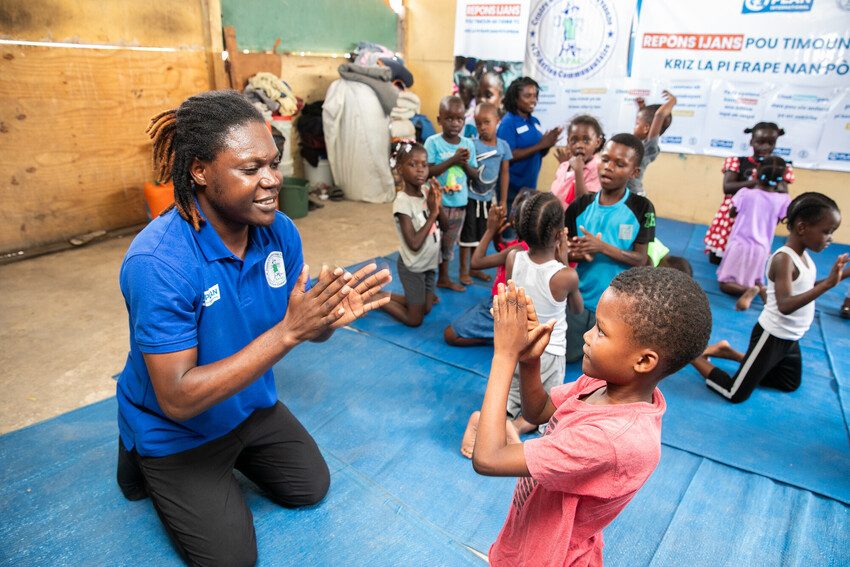 Plan International staff members with children in an internally displaced persons camp in Haiti