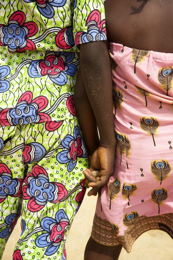 Girls holding hands on a beach in Togo.