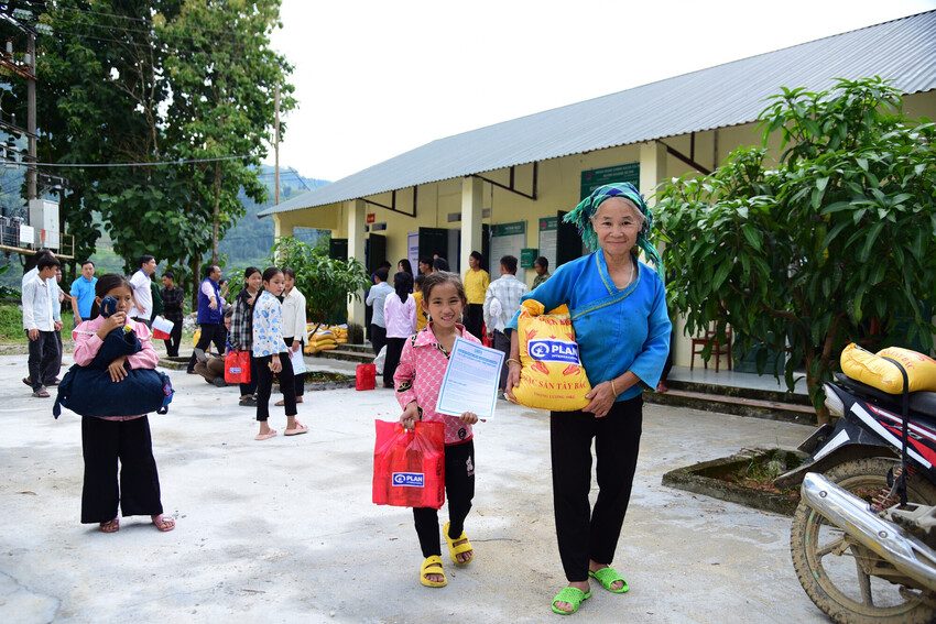 A woman and a child hold bags of disaster relief essentials. 