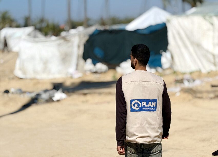 A Plan International staff member photographed walking from behind.