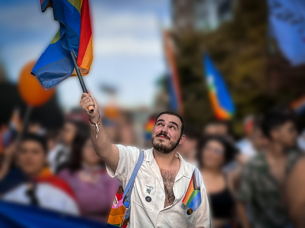 Armand waving an LGBTQI+ flag.