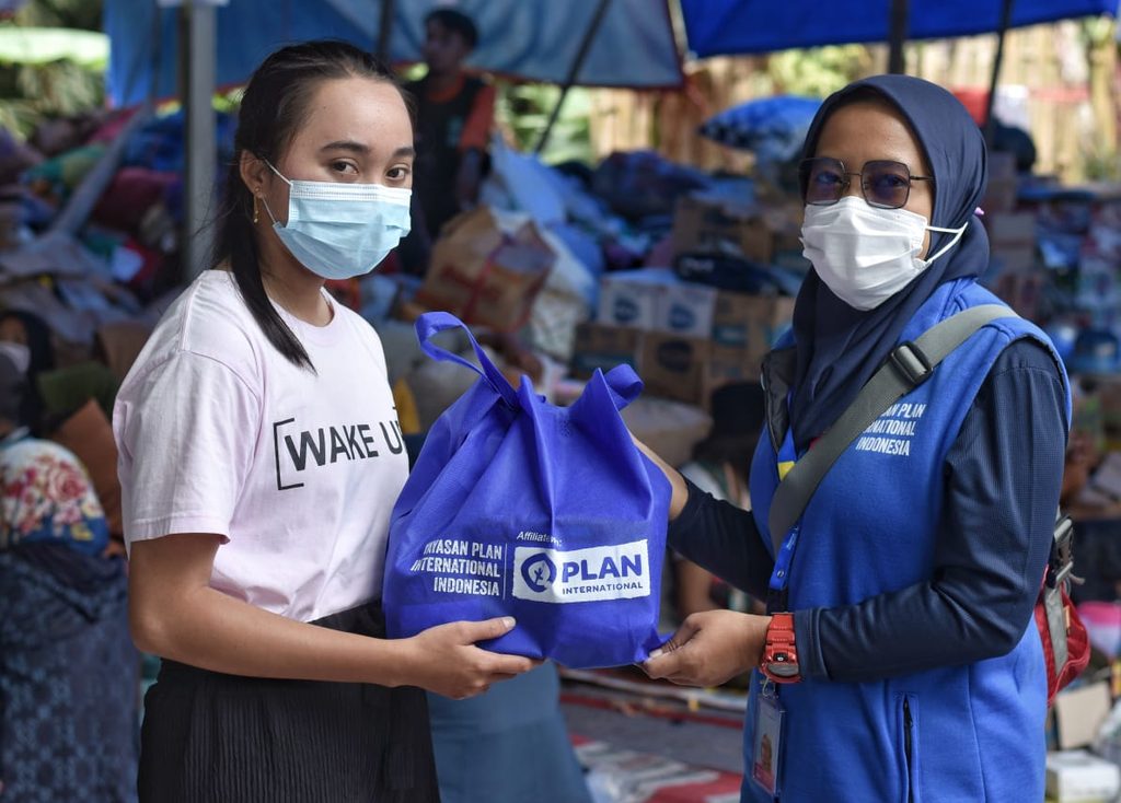 Maulinna hands a bag to a young woman.
