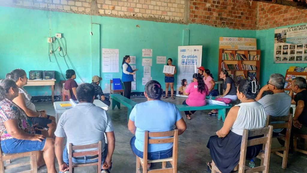 Roxanna and a woman stand at the front of a group hosting a session.
