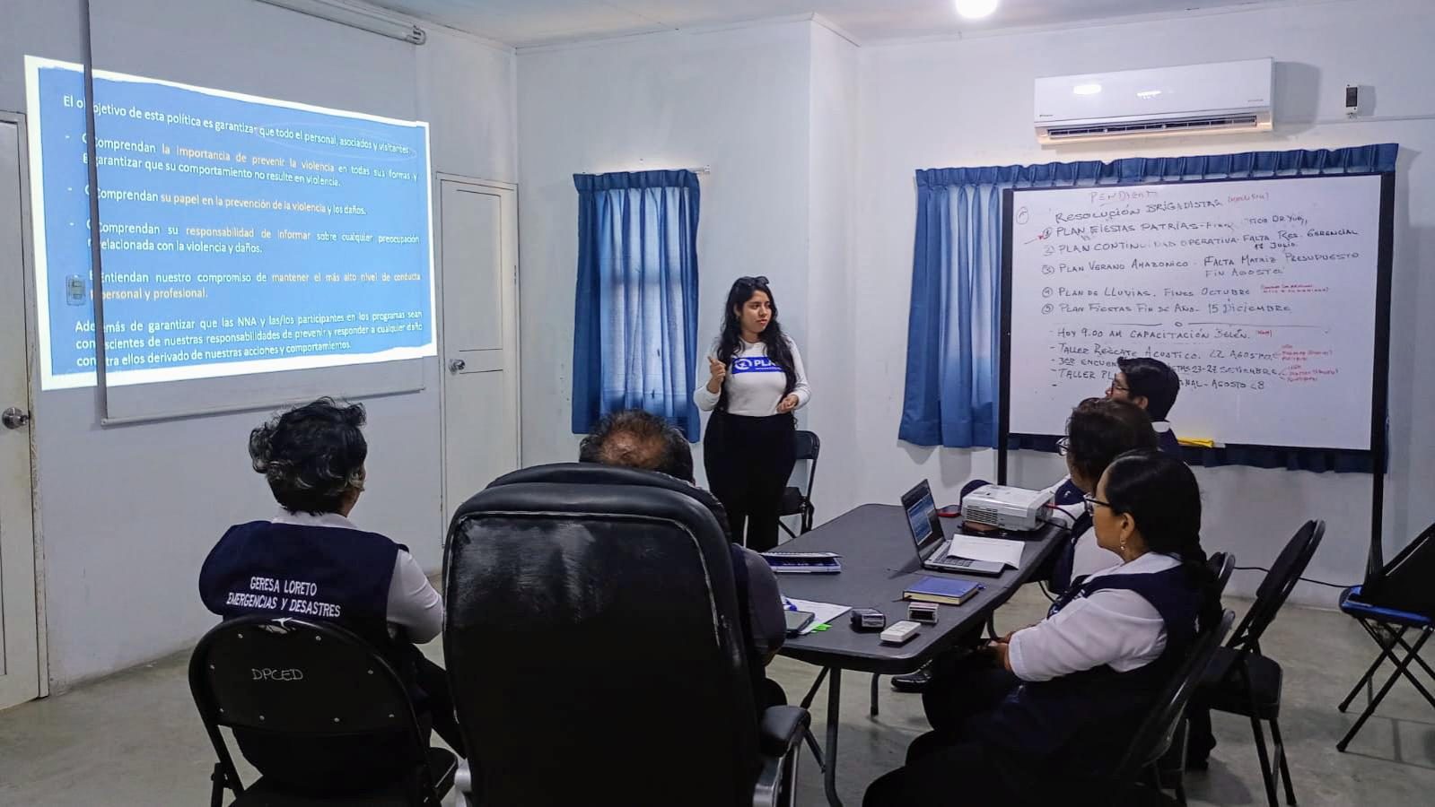 Roxanna stands in front of a presentation board, presenting to several people.