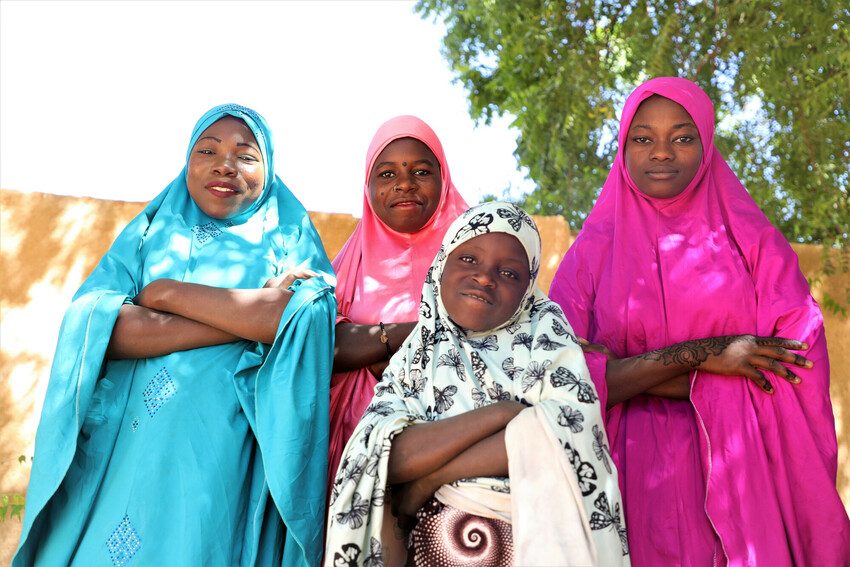 Four women and girls stand with their arms folded. 