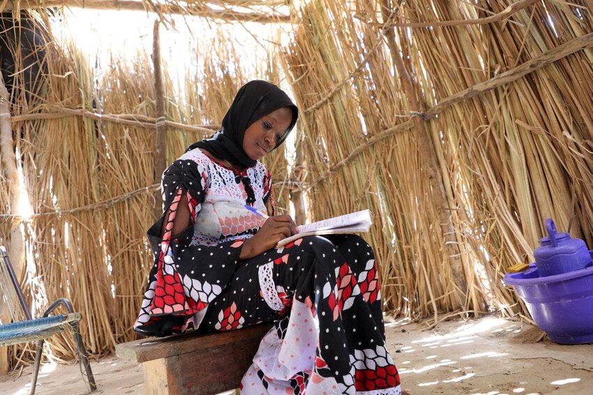 Mahawa writing in her textbook at home. 
