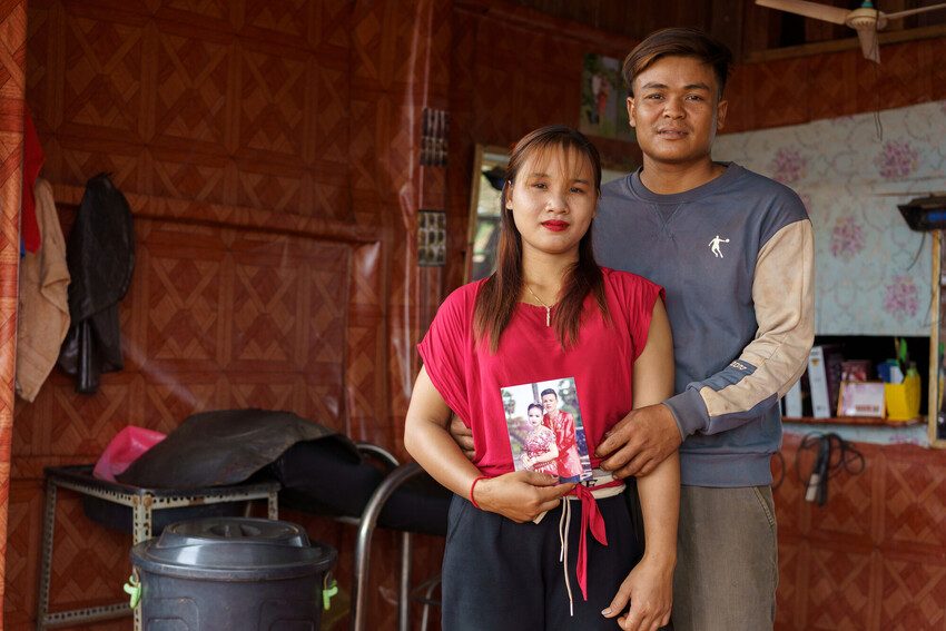 Pov standing with her husband holding up a photo. 