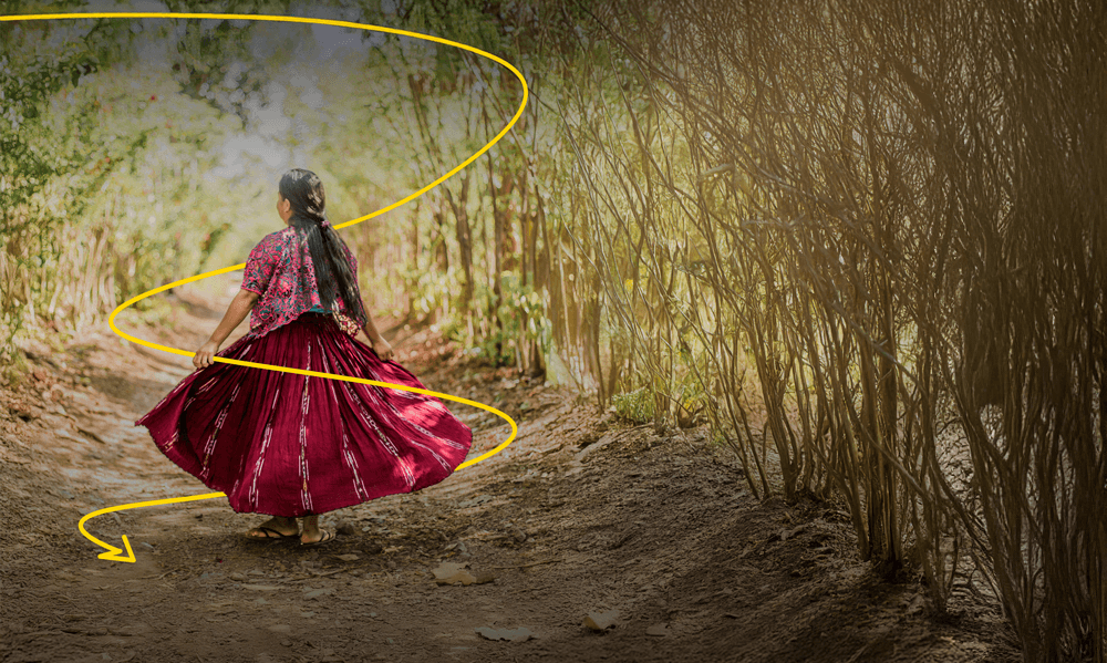 A woman in a dress standing in a amongst bushes. 