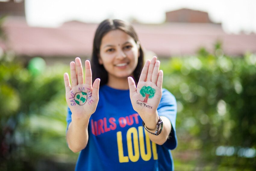 Girl has signs on her hands calling for people to save the environment.