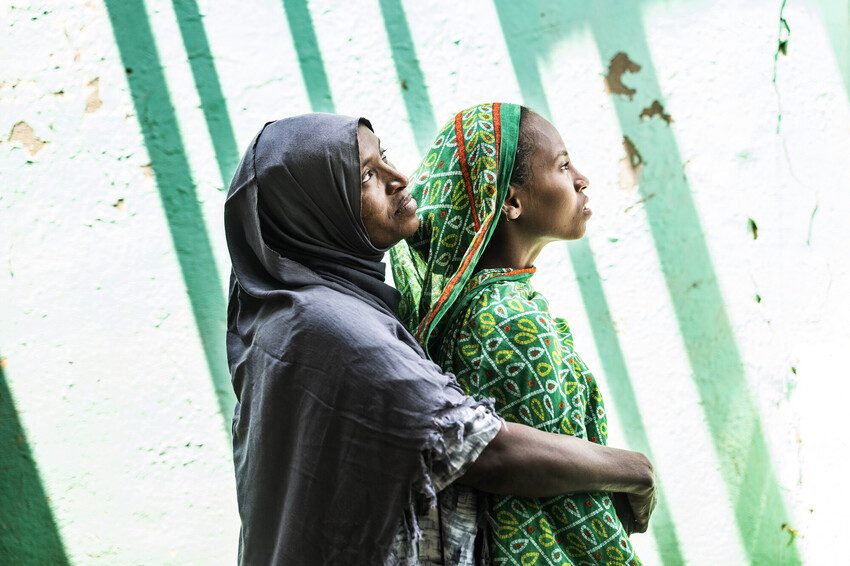 Shishig and her daughter Eman hug and stare into the distance.