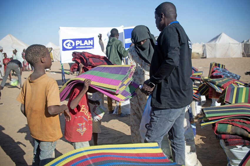 Plan staff distribute humanitarian aid to children and families in Sudan.