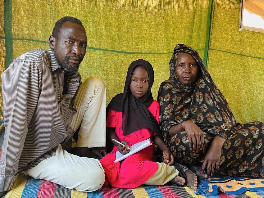 Fatima's parents helping her study in their new camp home.
