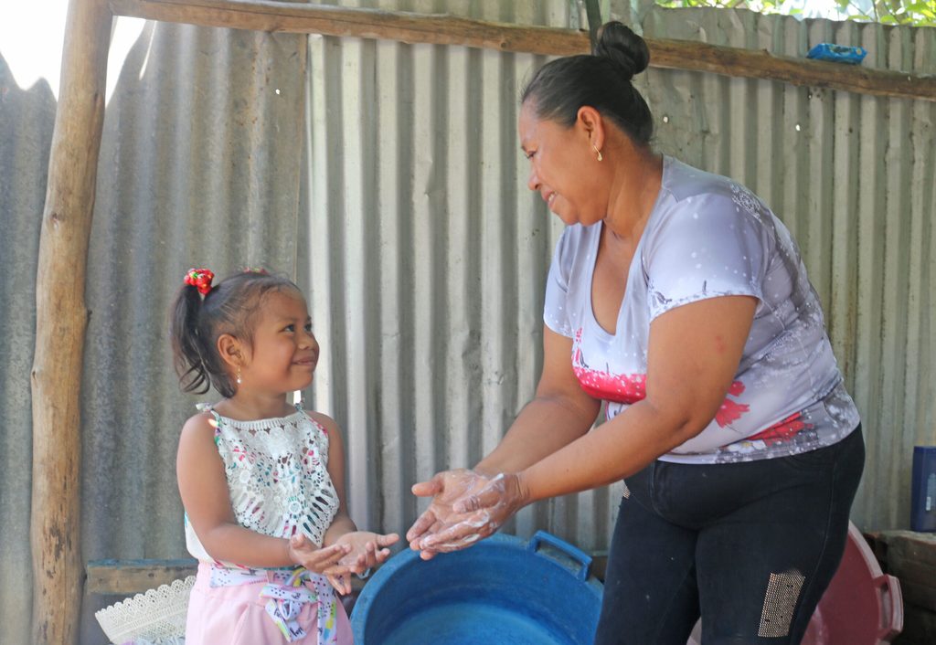 Sarvia mostrando a su hija el proceso del lavado de manos.