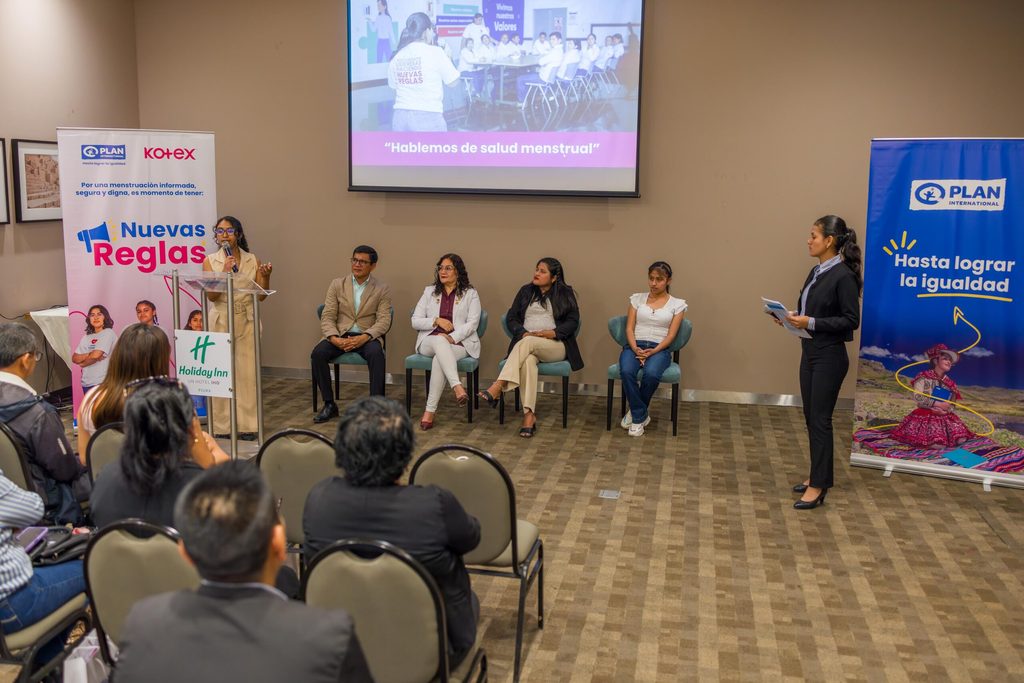 Una adolescente ofrece un discurso mientras otros ponentes permanecen sentados en sillas detrás.