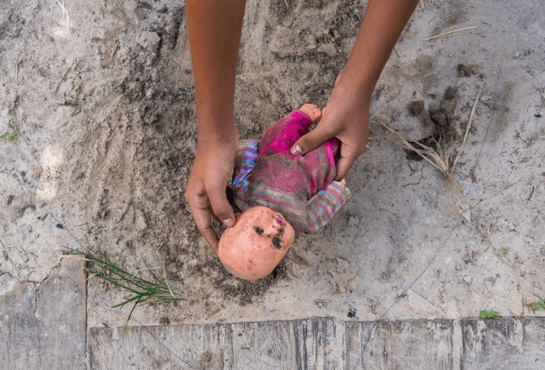 Muñeca olvidada y deteriorada, simulando la pérdida de la niñez causada por las uniones forzadas.